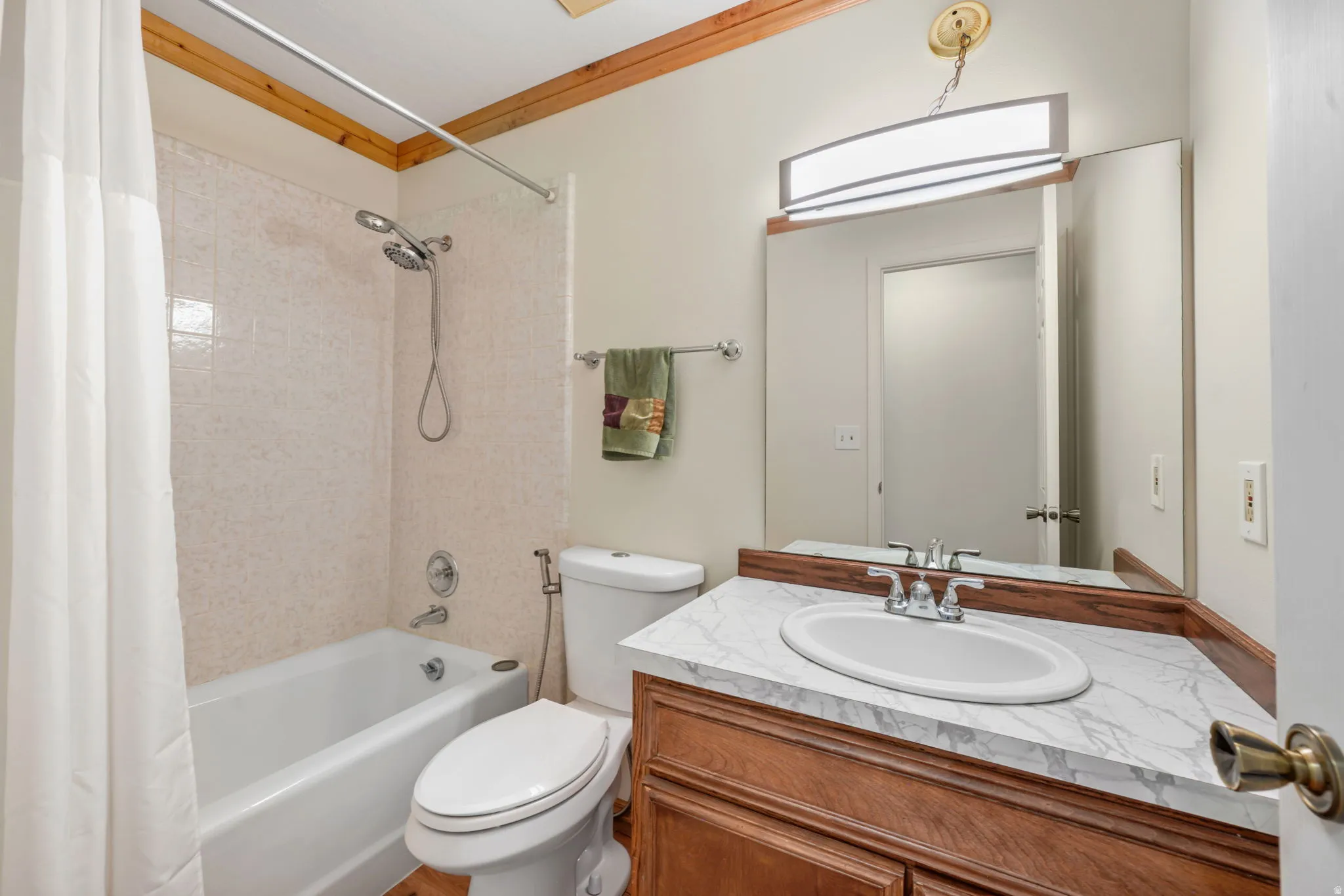 2nd Main floor bathroom featuring a wood-finish vanity with marble-topped countertop, oval undermount sink, and polished chrome fixtures