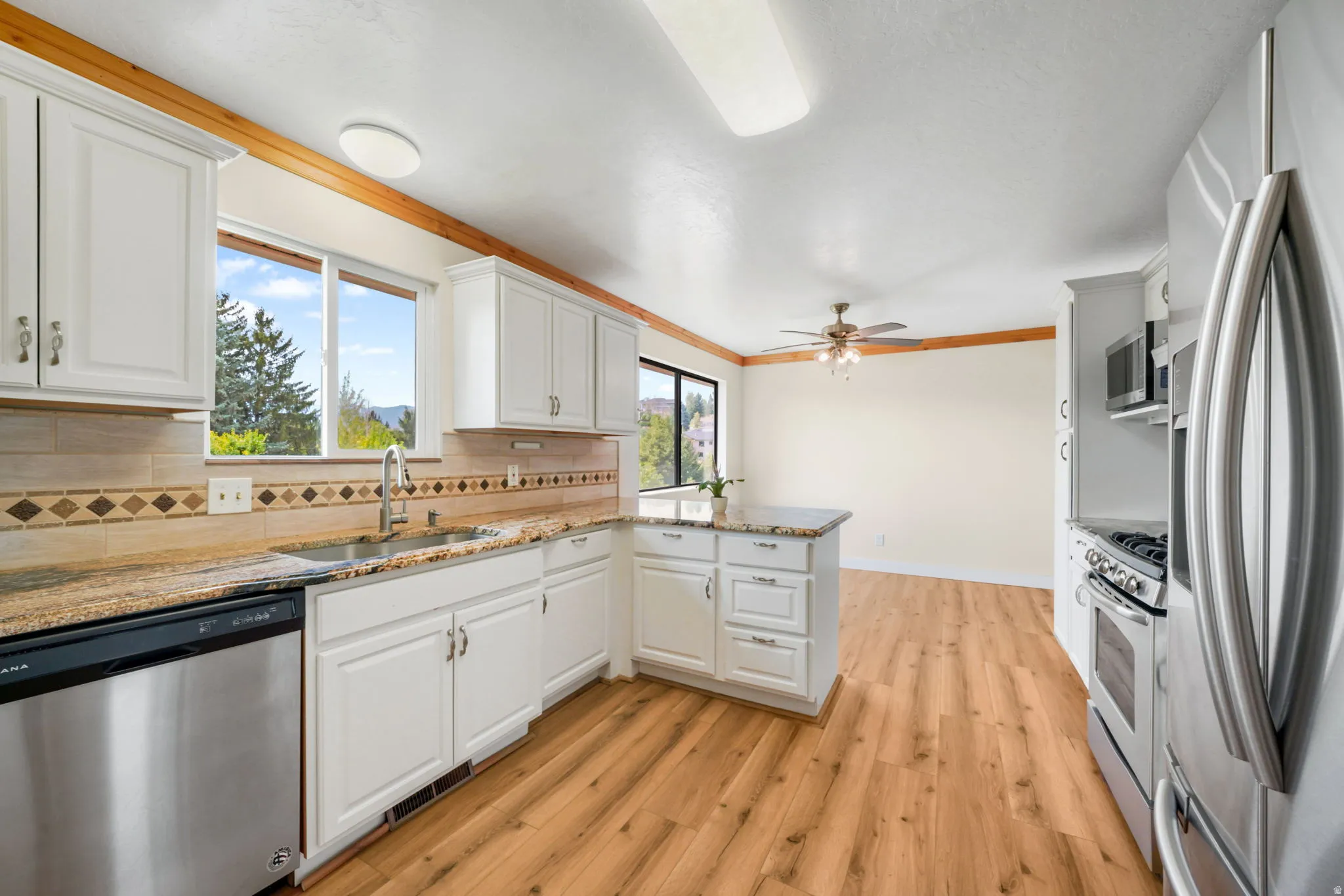 Kitchen featuring white cabinetry, stainless steel appliances, granite countertops, and wood-finish flooring
