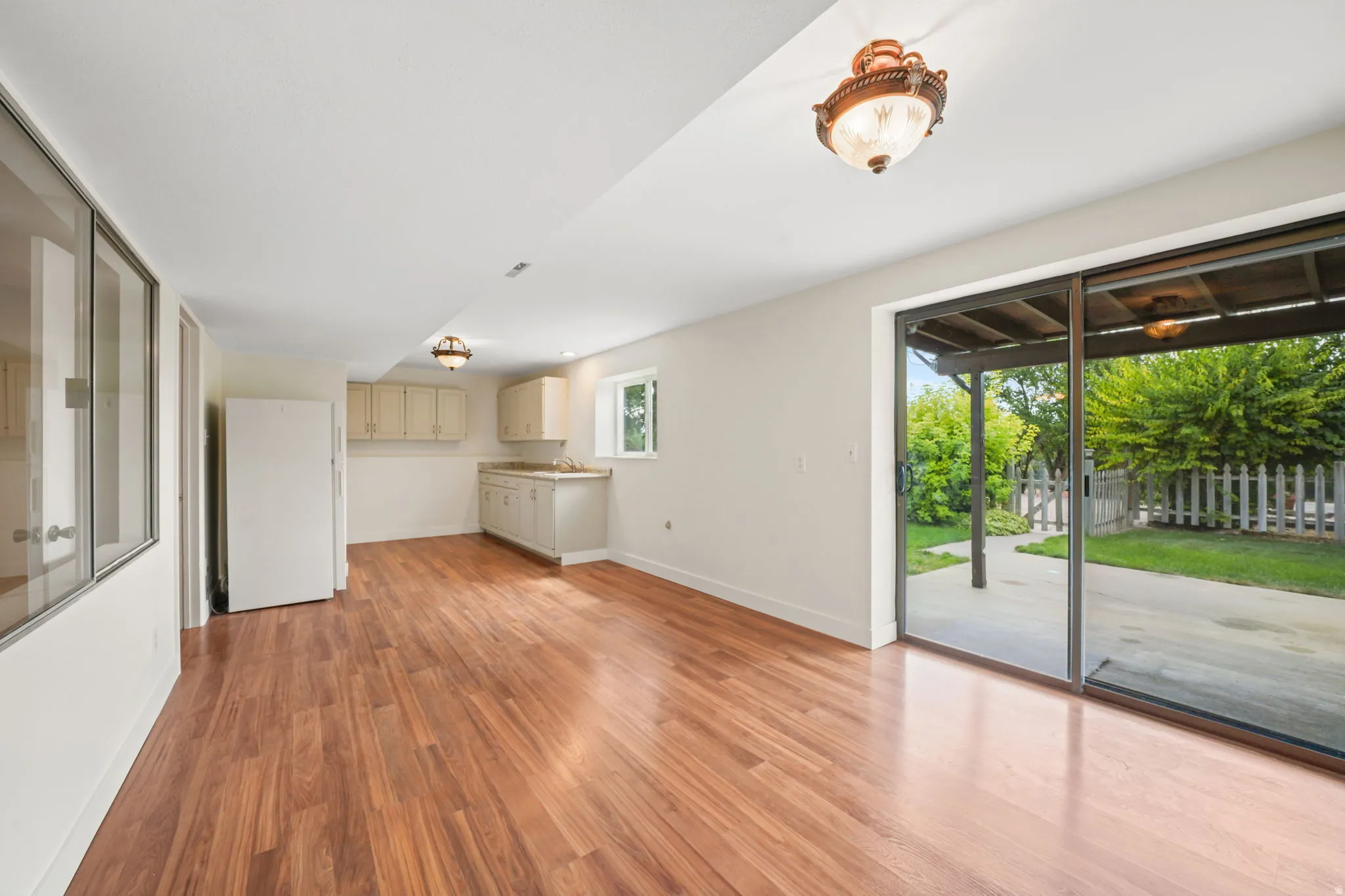 Basement Kitchen/dining area - Wood-finish flooring, Entry sliding glass door, built-in cabinetry, ceiling-mounted lighting, and a window