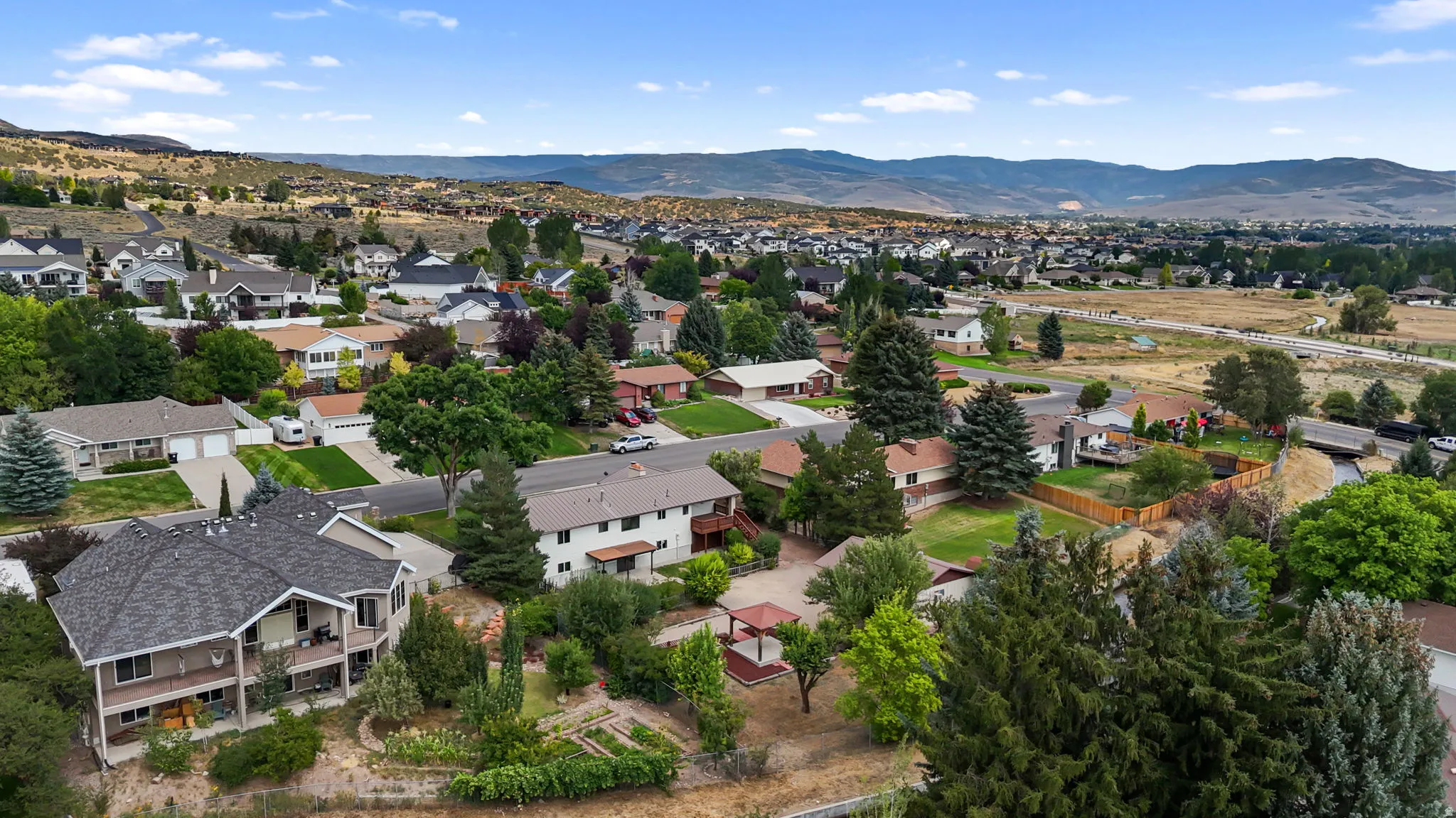Aerial view showcasing a residential neighborhood nestled against rolling foothills and mountain ranges