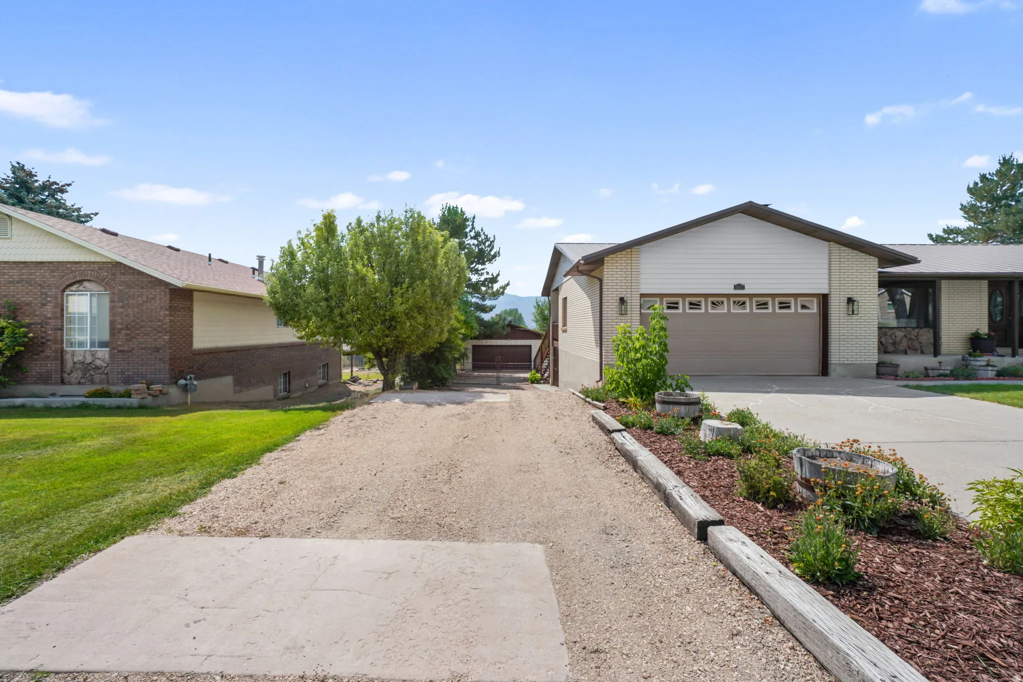 Brick exterior with a peaked roofline, attached garage, and a  driveway to access the back yard
