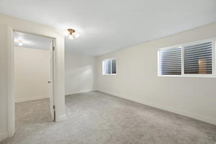 2nd Bedroom w/Walkin closet, Spacious room with light-colored carpeting, white painted walls, two egress windows, and a flush mount ceiling light fixture