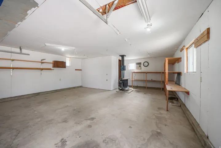Detached Garage/Shop with Large Concrete flooring with built-in shelving, a wood-burning stove, window mount A/C and multiple windows