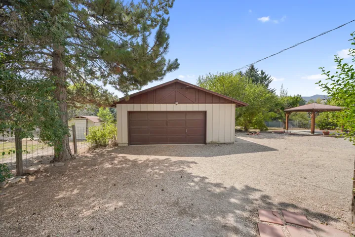 Detached garage/shop with a brown sectional door and gabled roof.