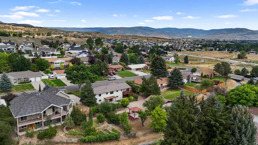 Aerial view showcasing a residential neighborhood nestled against rolling foothills and mountain ranges