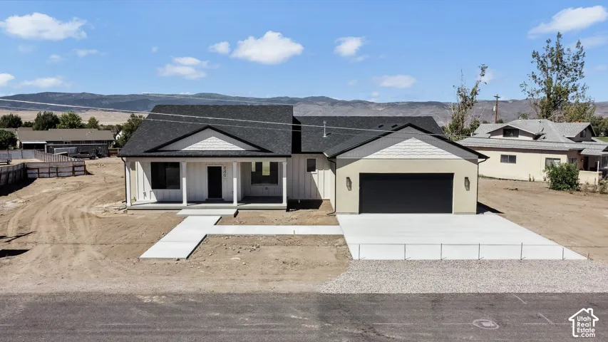 Contemporary exterior with a covered porch, board and batten siding, attached garage, concrete driveway, and concrete walkway
