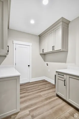 Recessed ceiling lighting, wood-finish flooring, light-toned cabinetry, white countertops, and contemporary black hardware