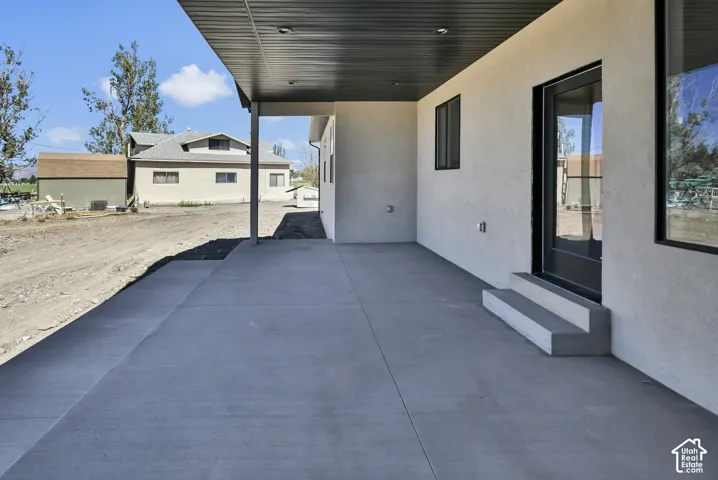 Covered concrete patio with recessed lighting, stucco exterior, and black-framed windows