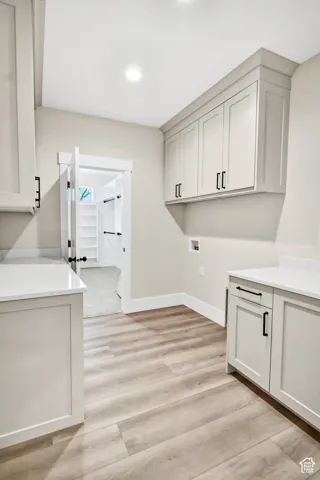 Wood-finish flooring, recessed lighting, shaker-style cabinetry, white countertops, and a door to the walk-in master closet