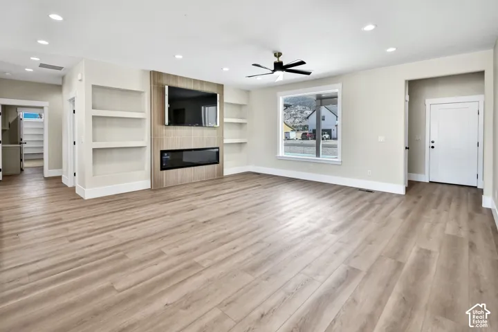 Wood-finish flooring throughout, complemented by a tiled media wall with an integrated electric fireplace and built-in shelving