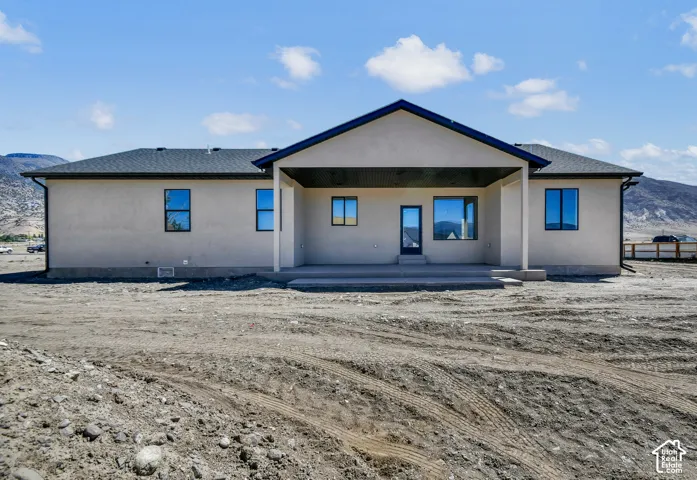 Stucco exterior with a dark shingle roof, featuring a covered concrete patio
