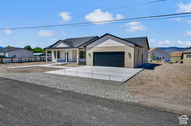 Contemporary exterior with a dark shingle roof, attached garage, and a covered front porch featuring white columns