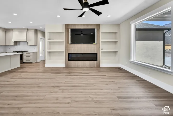 Open-concept living area with wood-finish flooring, recessed lighting, and a black ceiling fan