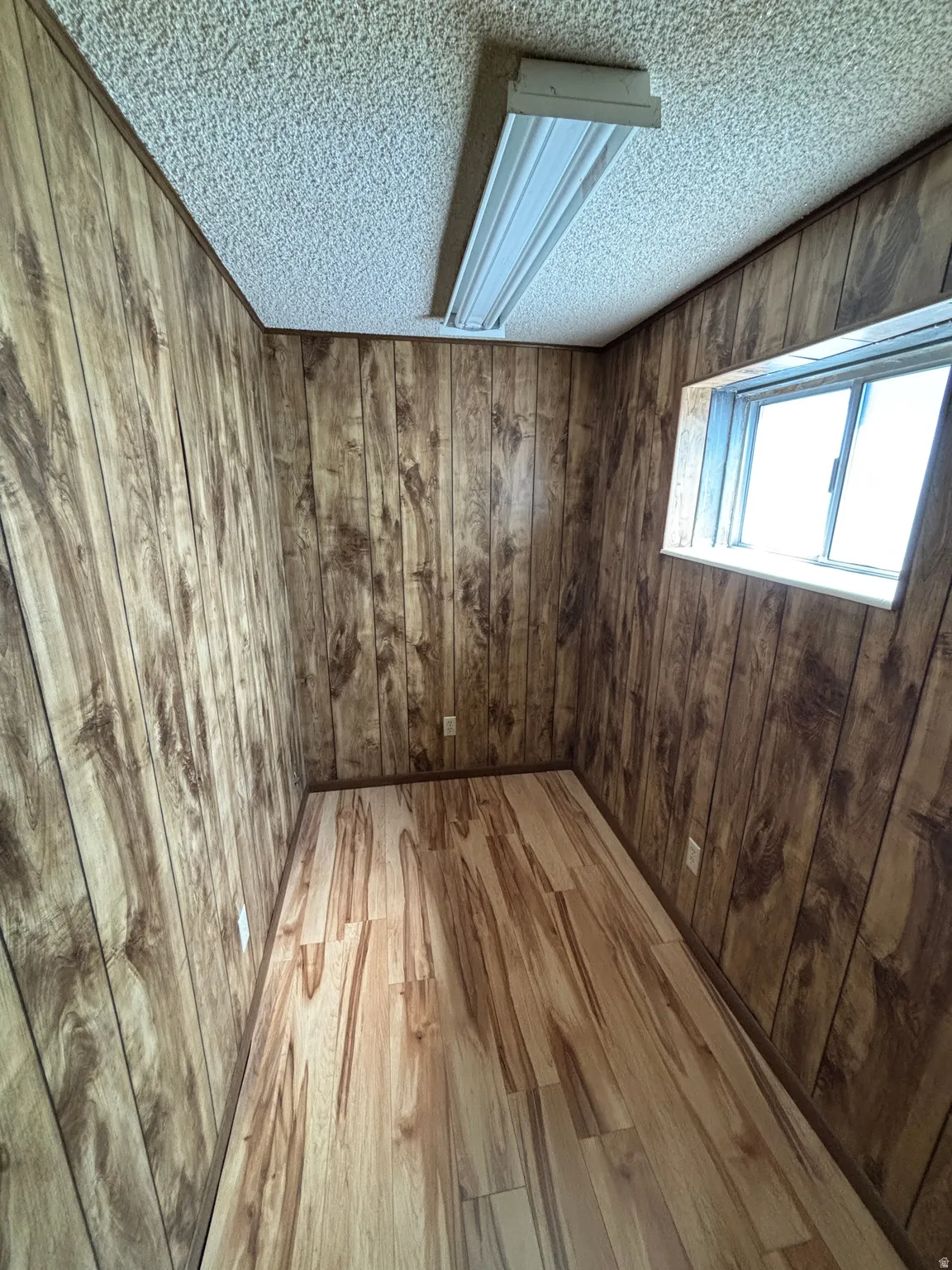 Wood-finish flooring, wood-panel walls, and a window for natural light