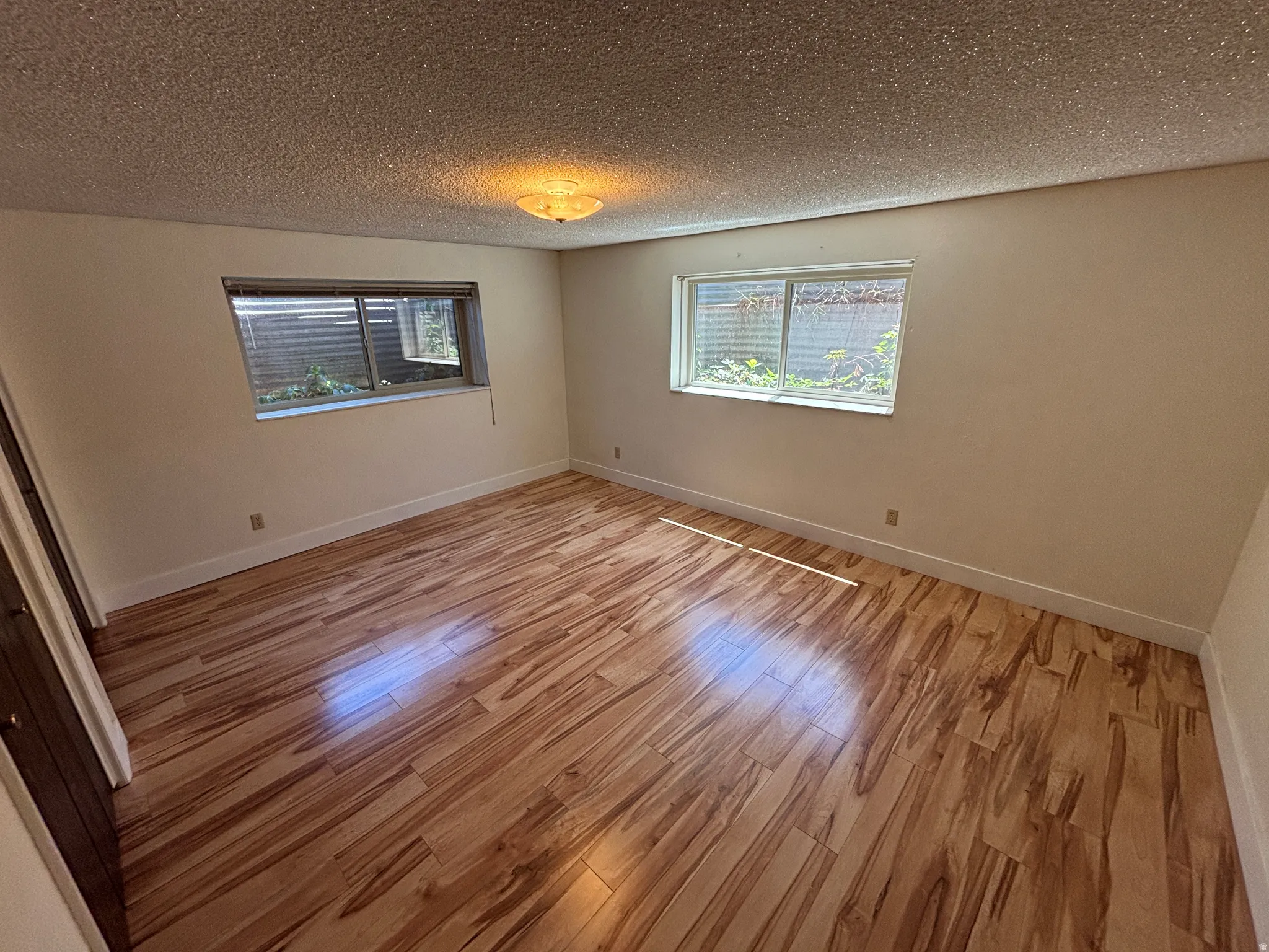 Wood-finish flooring, recessed windows, wall-mounted light fixture, and light-toned wall finishes
