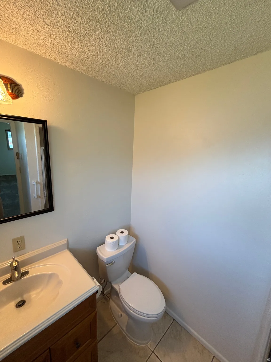Vanity with integrated sink and chrome faucet, framed mirror, and tile flooring