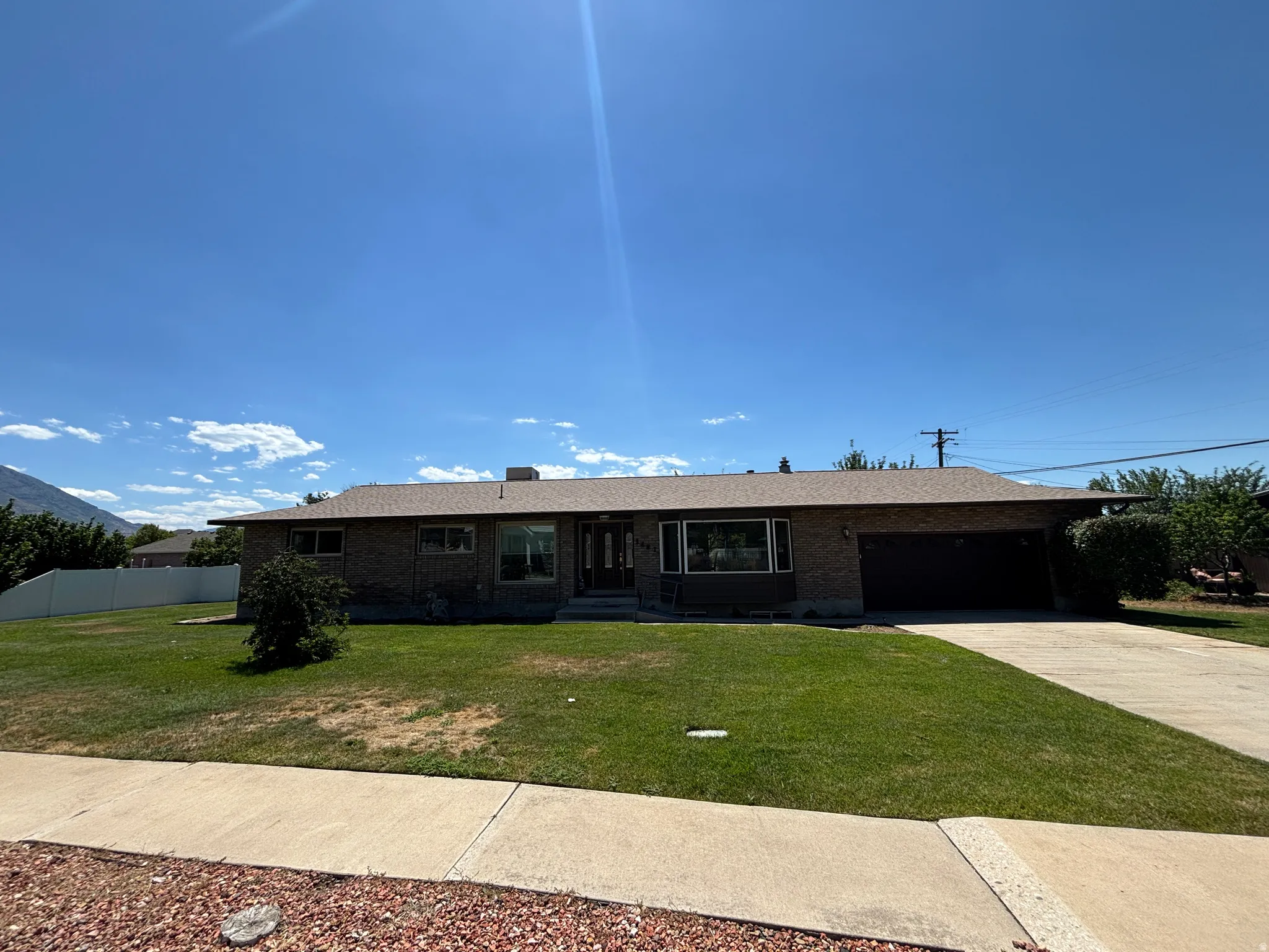 Brick exterior with a brown shingle roof, integrated garage, and concrete driveway