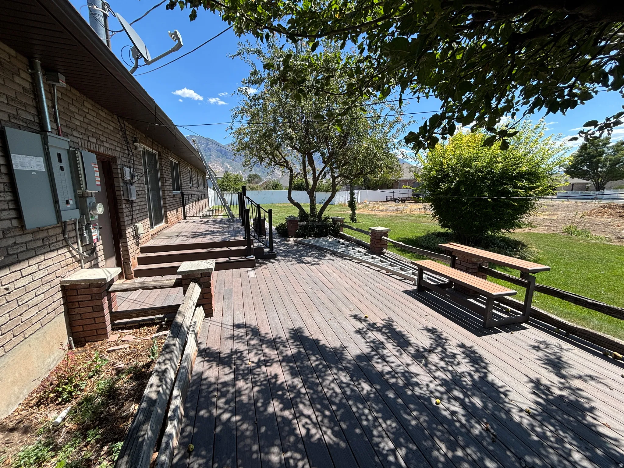 Expansive wood-finish deck with integrated seating, brick accent pillars, and a multi-level design