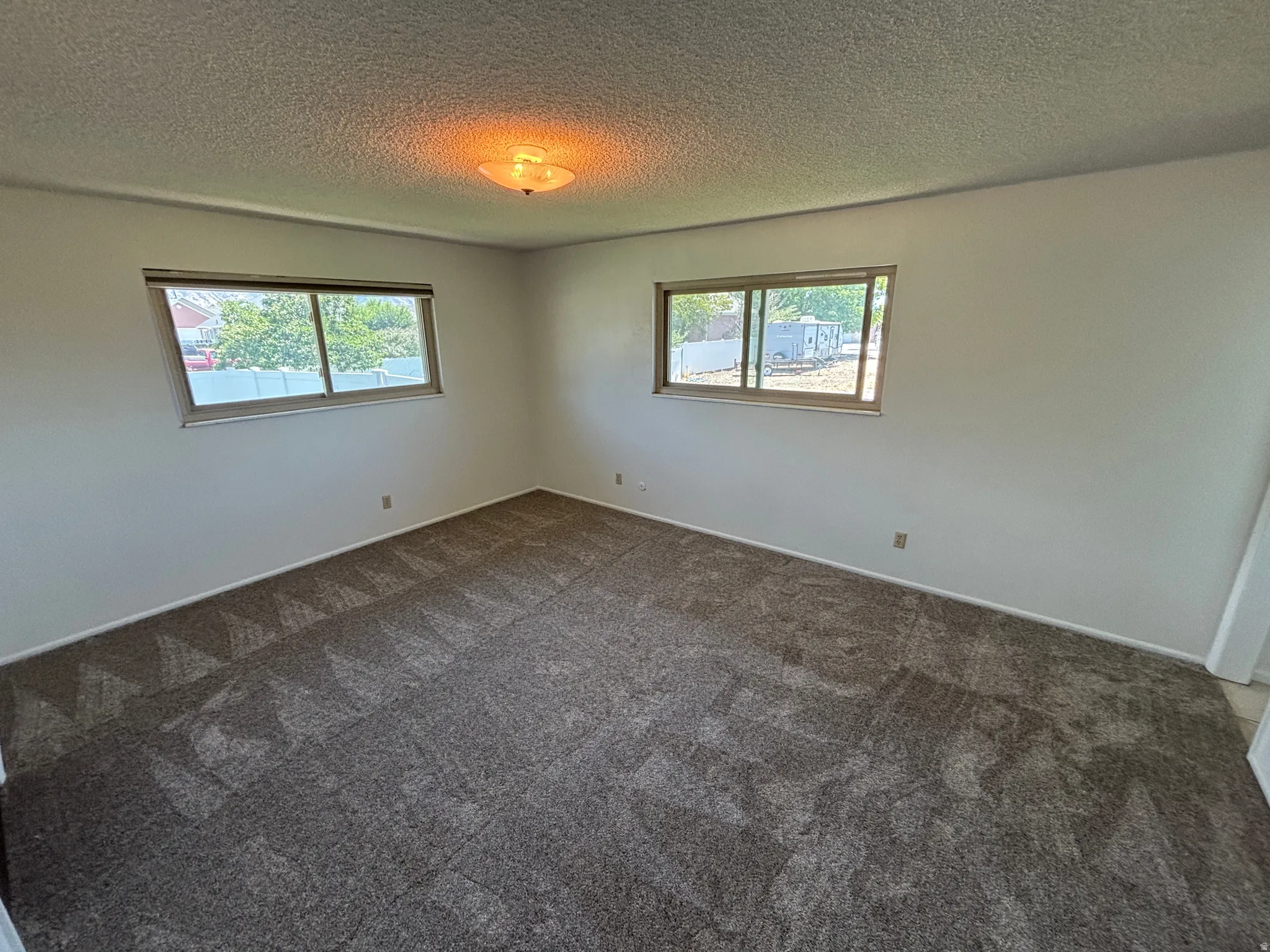 Neutral wall tones with two windows, textured ceiling, and patterned carpeting
