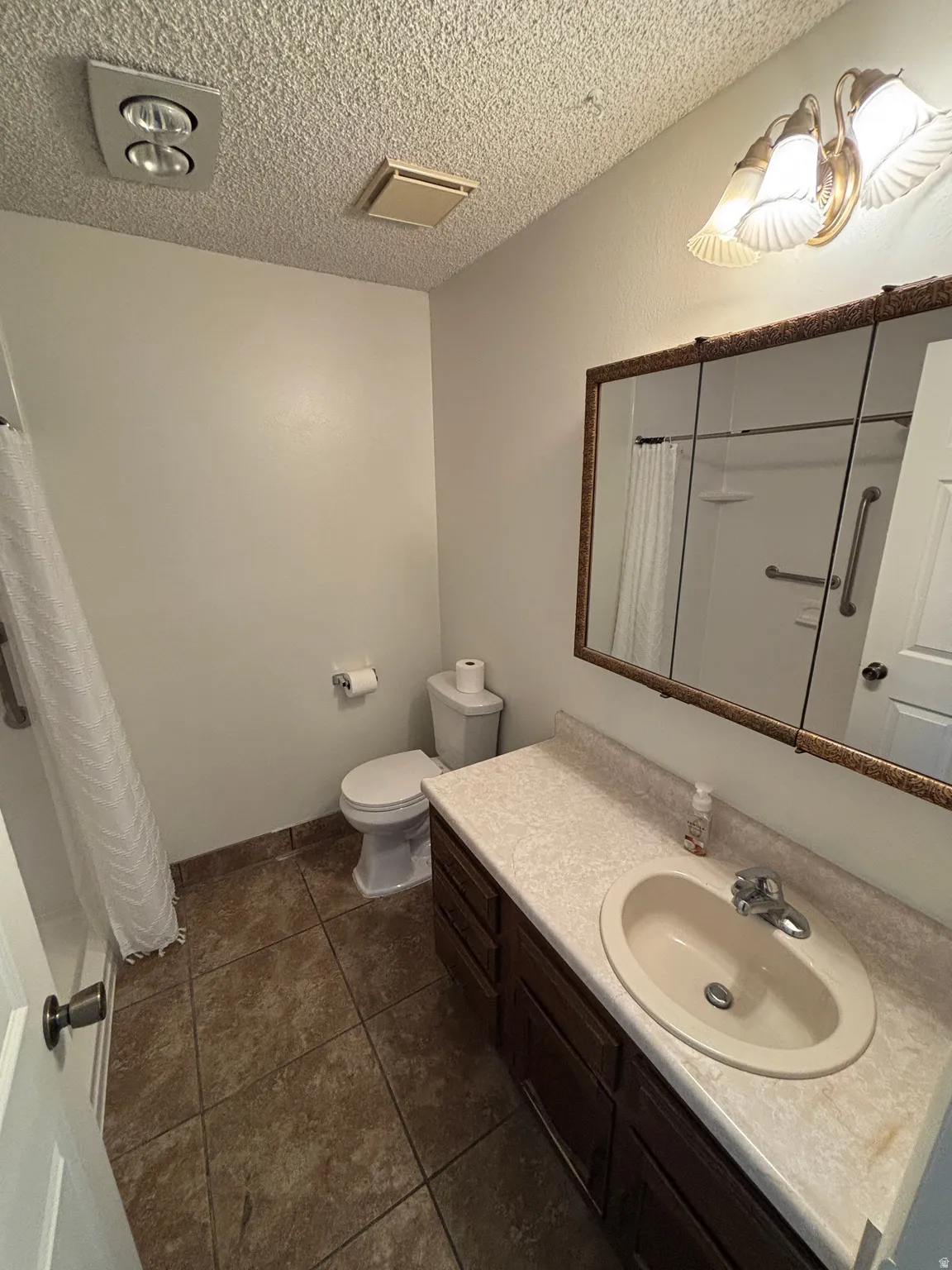 Bathroom featuring a wood-finish vanity with dual-sink configuration, quartz countertop, and framed mirror