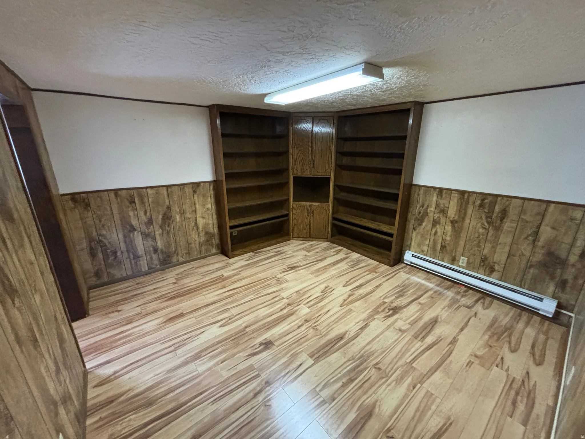 Wood-finish flooring, built-in shelving, wood paneling, and ceiling-mounted fluorescent lighting