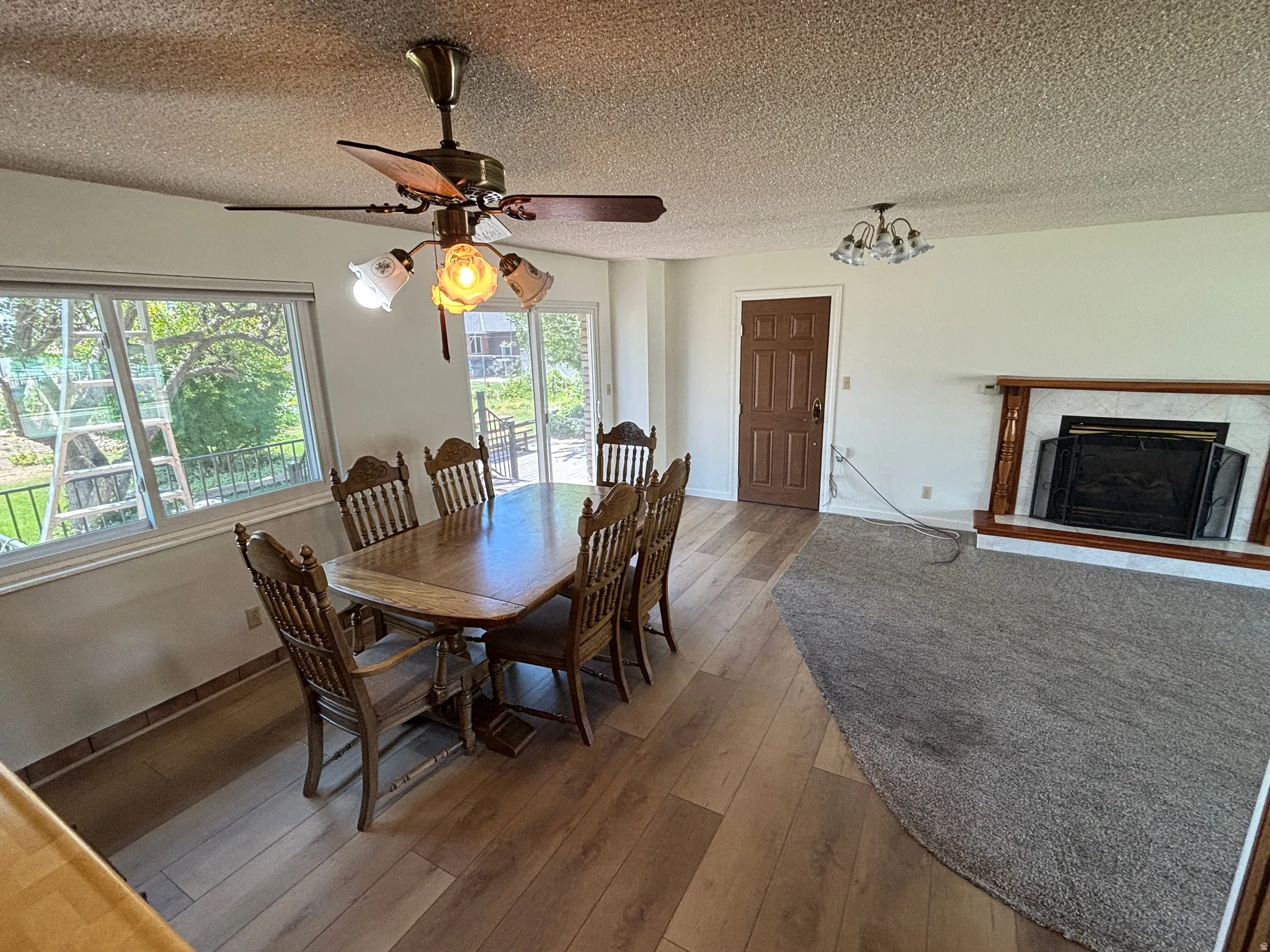 Wood-finish flooring, ceiling fan with integrated lighting, built-in fireplace with a hearth, and sliding glass door
