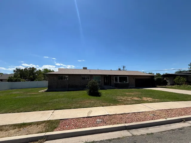 Brick exterior with an attached garage, featuring a paved driveway and a front lawn