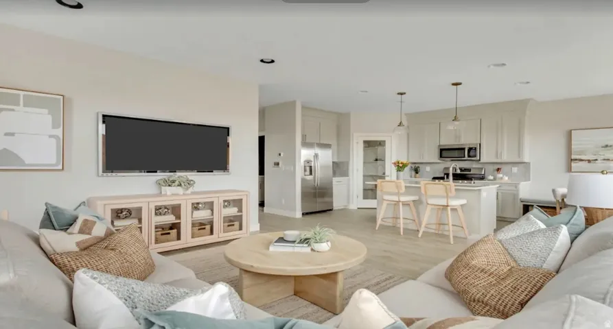 Open-concept living space featuring wood-finish flooring. This home is under construction. Pictures are of a similar home.