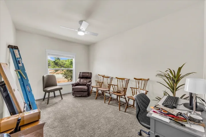 Carpeted room featuring a ceiling fan with integrated lighting, a window with a white frame, and light-colored walls