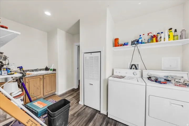 Laundry area featuring wood-finish flooring, built-in shelving, and a utility sink with storage cabinetry