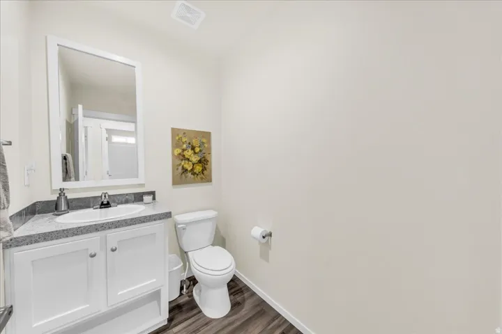 White vanity with shaker-style cabinetry, granite-finish countertop, and undermount sink