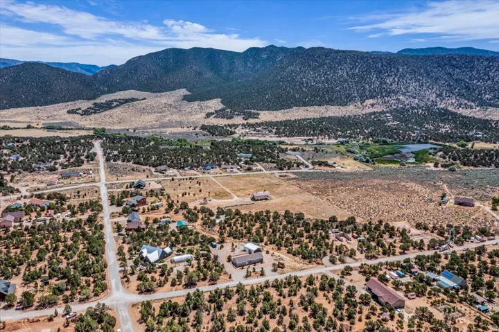 Expansive landscape featuring scattered residential properties, established roadways, natural terrain with varied vegetation, and distant mountain ranges