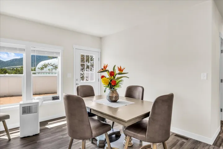 Bright dining area with wood-finish flooring, white trim, and a glass-paneled exterior door