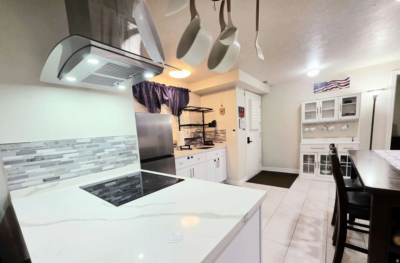 Kitchen featuring a built-in cooktop, white cabinetry, a decorative tile backsplash, white countertops, and tile flooring