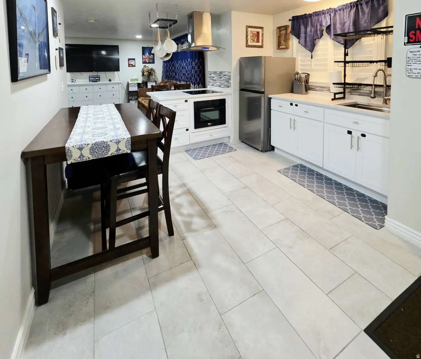 Contemporary kitchen featuring white cabinetry, light-toned tile flooring, stainless steel appliances, a built-in oven, and a tiled backsplash