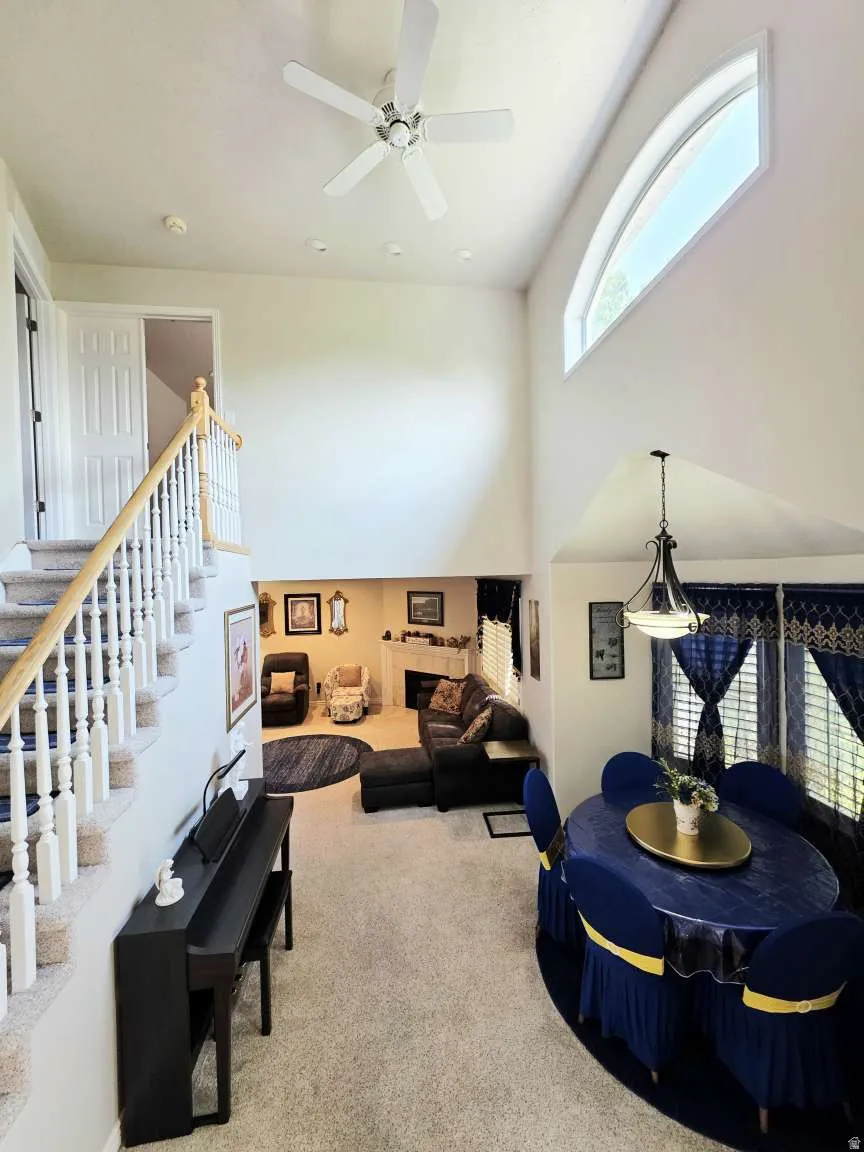 Two-story ceiling, arched window, staircase with wood handrail, recessed lighting, and a ceiling fan
