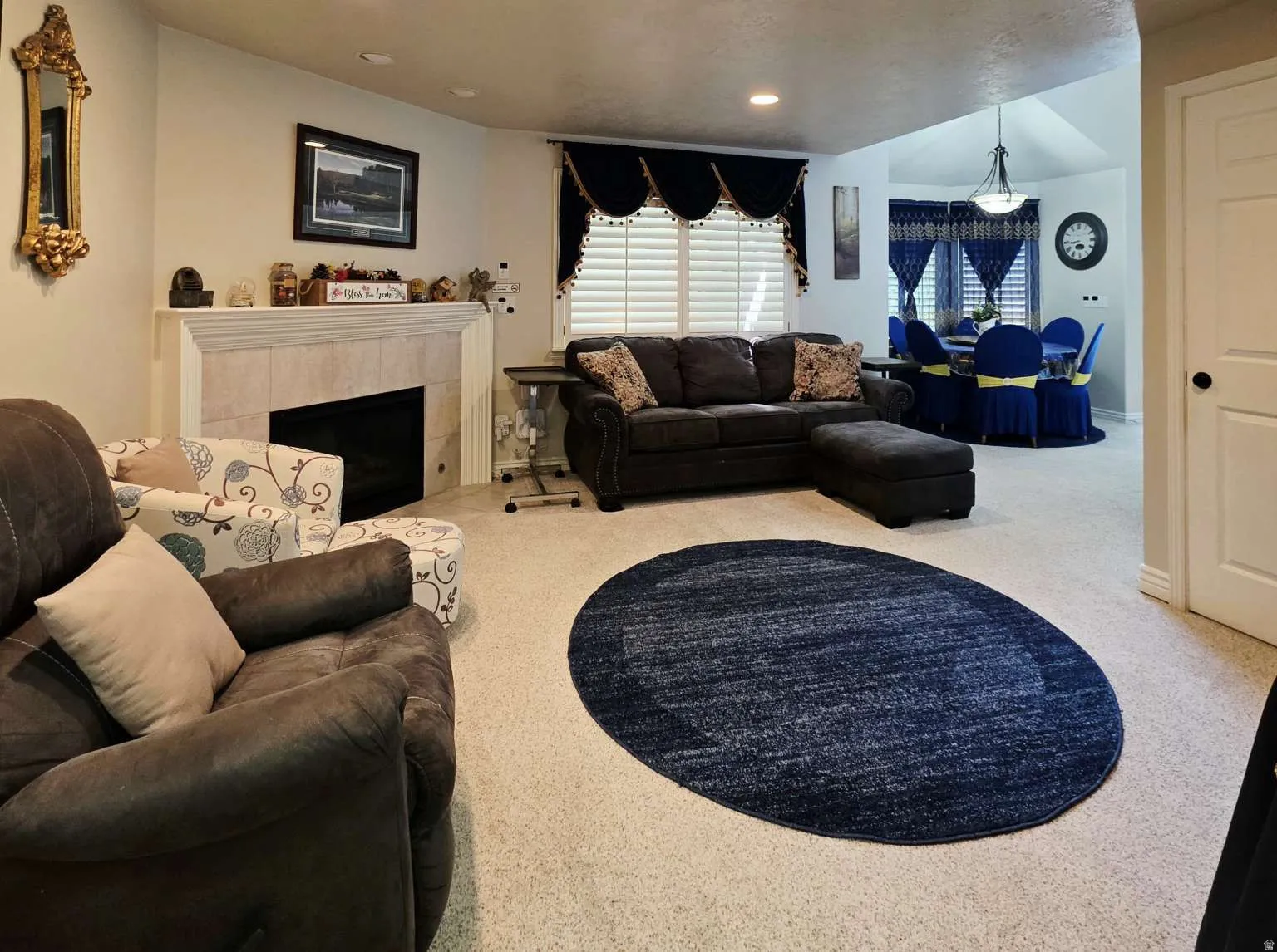 Recessed lighting, fireplace with tile surround, white mantel, window with plantation shutters, vaulted ceiling