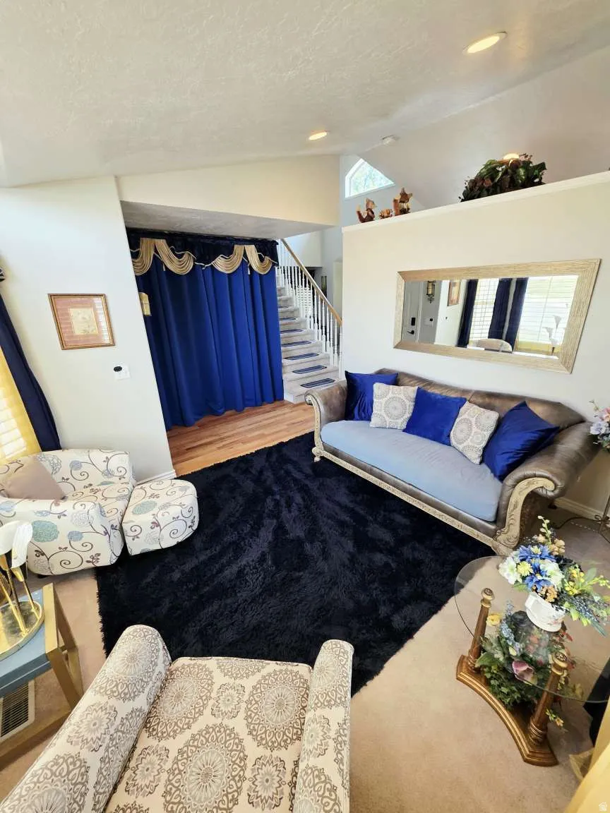 Vaulted ceilings with recessed lighting, staircase with white risers and wood-finish handrail, and an upper-level architectural window