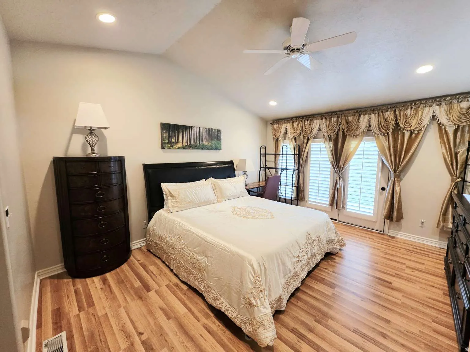 Vaulted ceiling with recessed lighting, wood-finish flooring, ceiling fan, and double French doors with plantation shutters