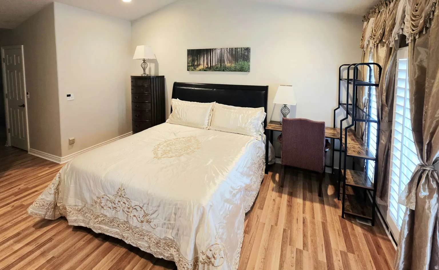 Wood-finish flooring throughout, vaulted ceiling, and white door with black hardware