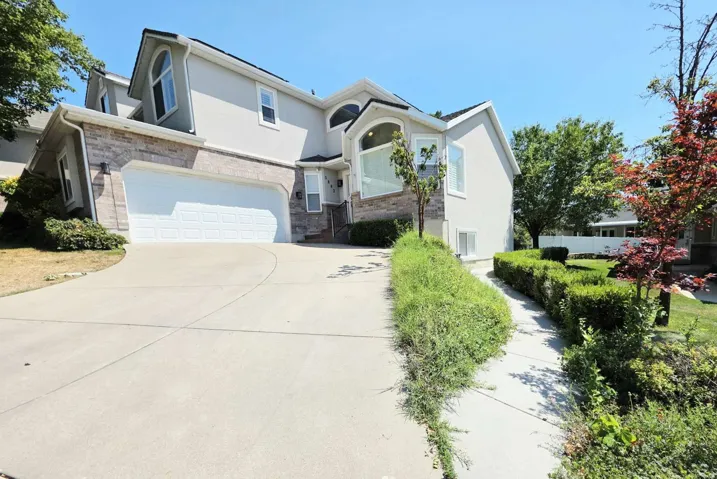 Stucco and stone facade with arched windows, an attached two-car garage, and a concrete driveway