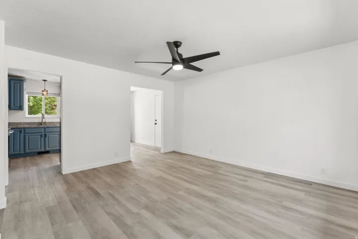 Spacious room featuring wood-finish flooring, a modern ceiling fan, and white painted walls