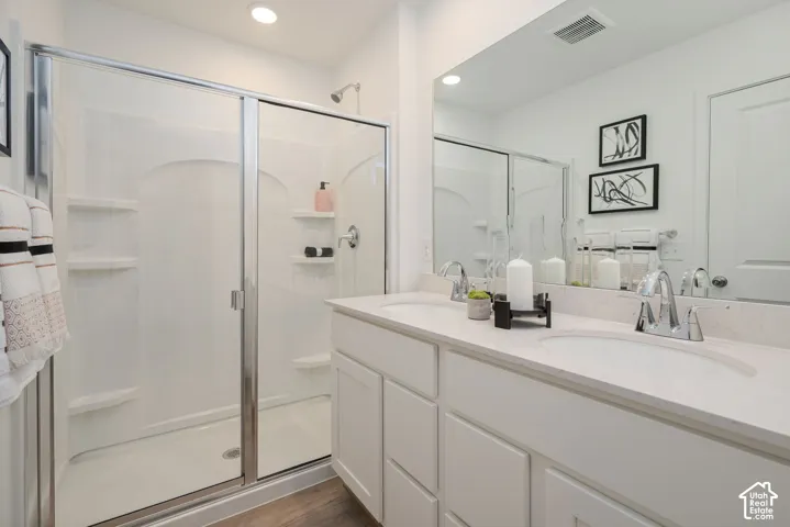 Double vanity with integrated sinks, white cabinetry, chrome fixtures, and a glass-enclosed shower