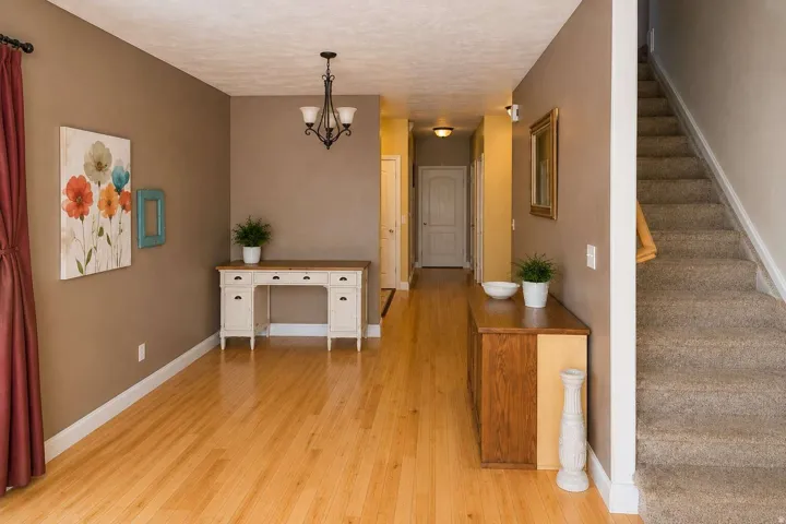 Hardwood flooring extends through the main hallway, complemented by a contemporary chandelier