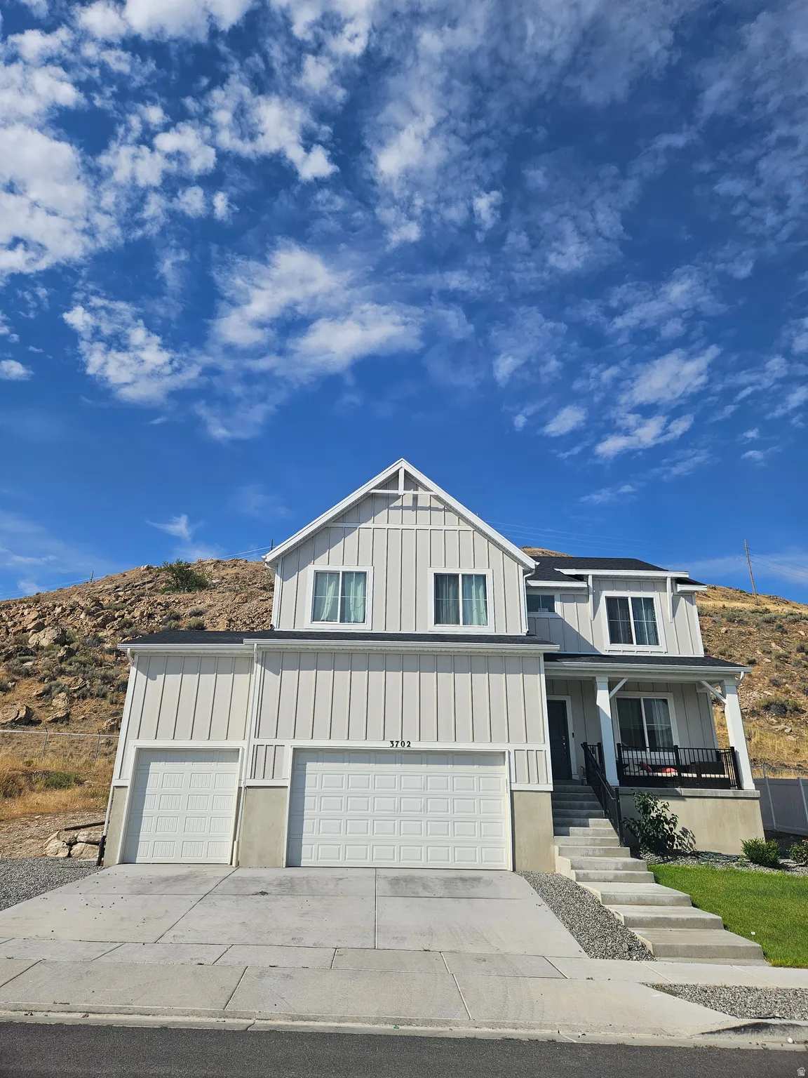 Two-story residence featuring a covered entry porch, multiple garage bays, and a concrete driveway