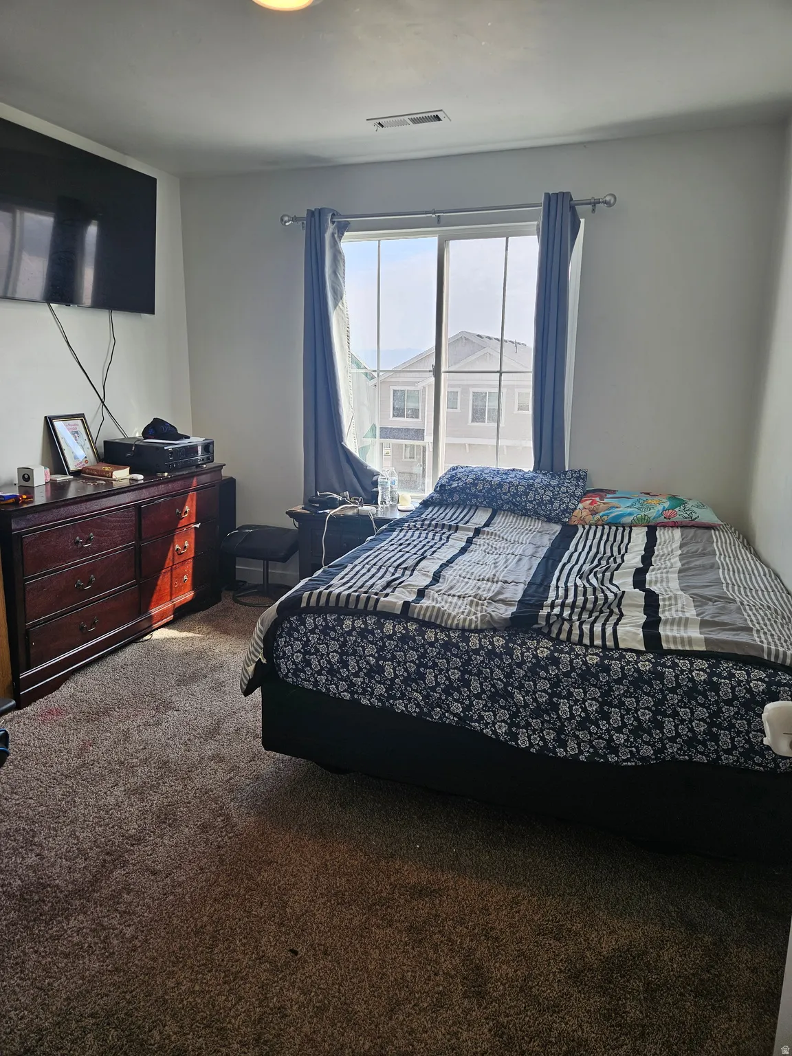 Carpeted room featuring a ceiling-mounted light fixture and a window with vertical blinds