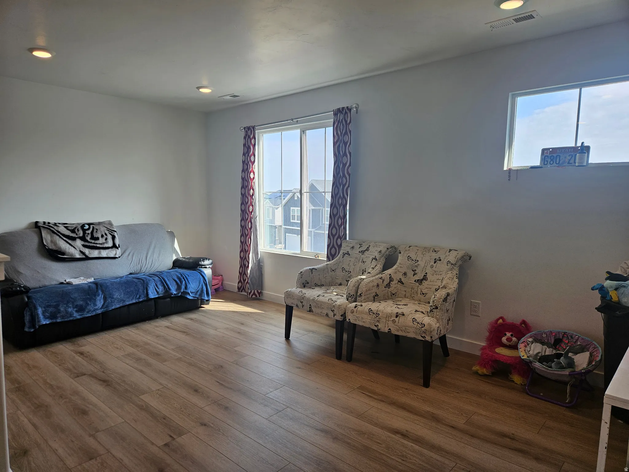 Recessed lighting illuminates the space, featuring wood-finish flooring, white walls, and multiple windows