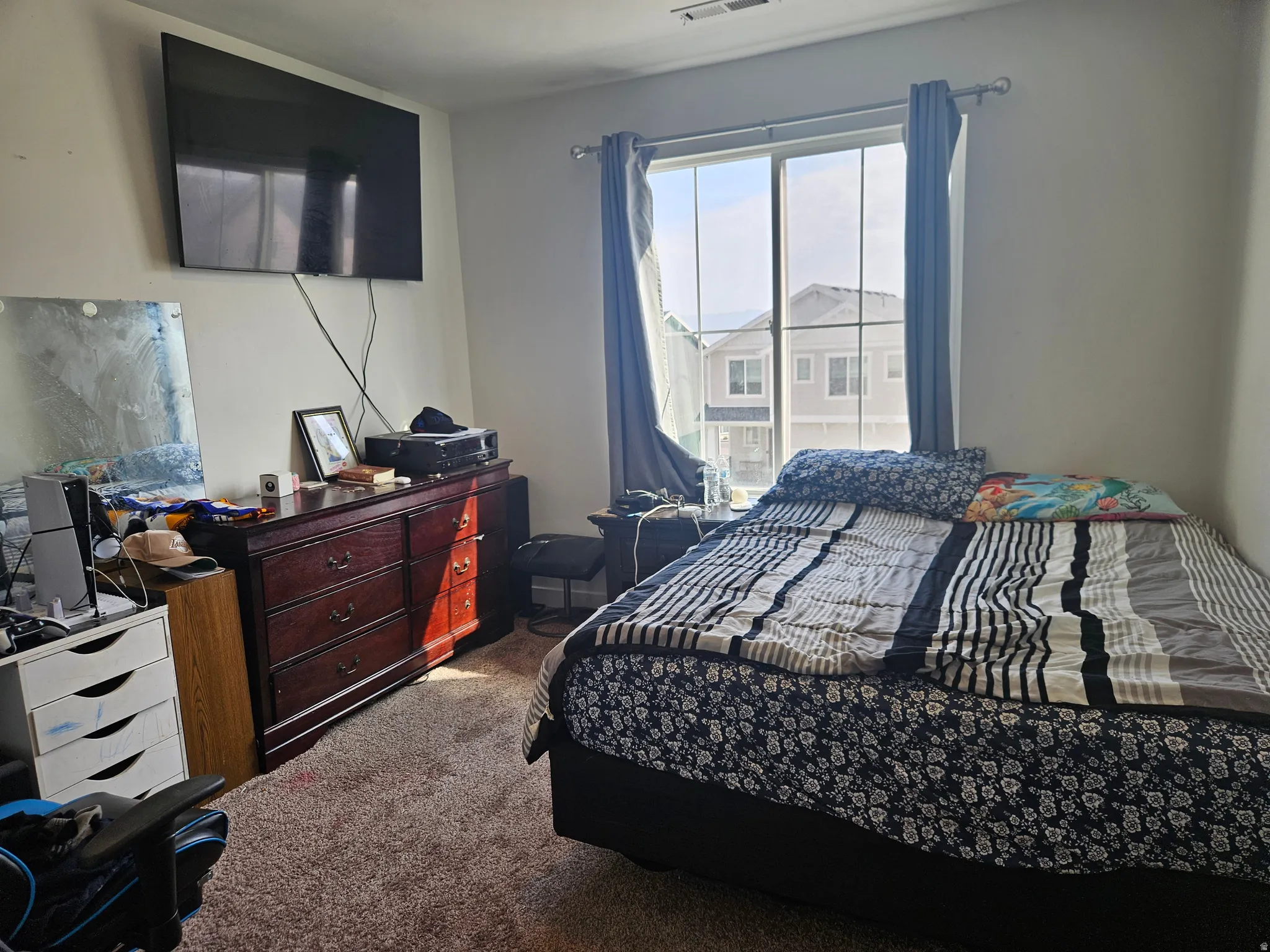 Wall-mounted television fixture, large window with natural light, and carpeted flooring