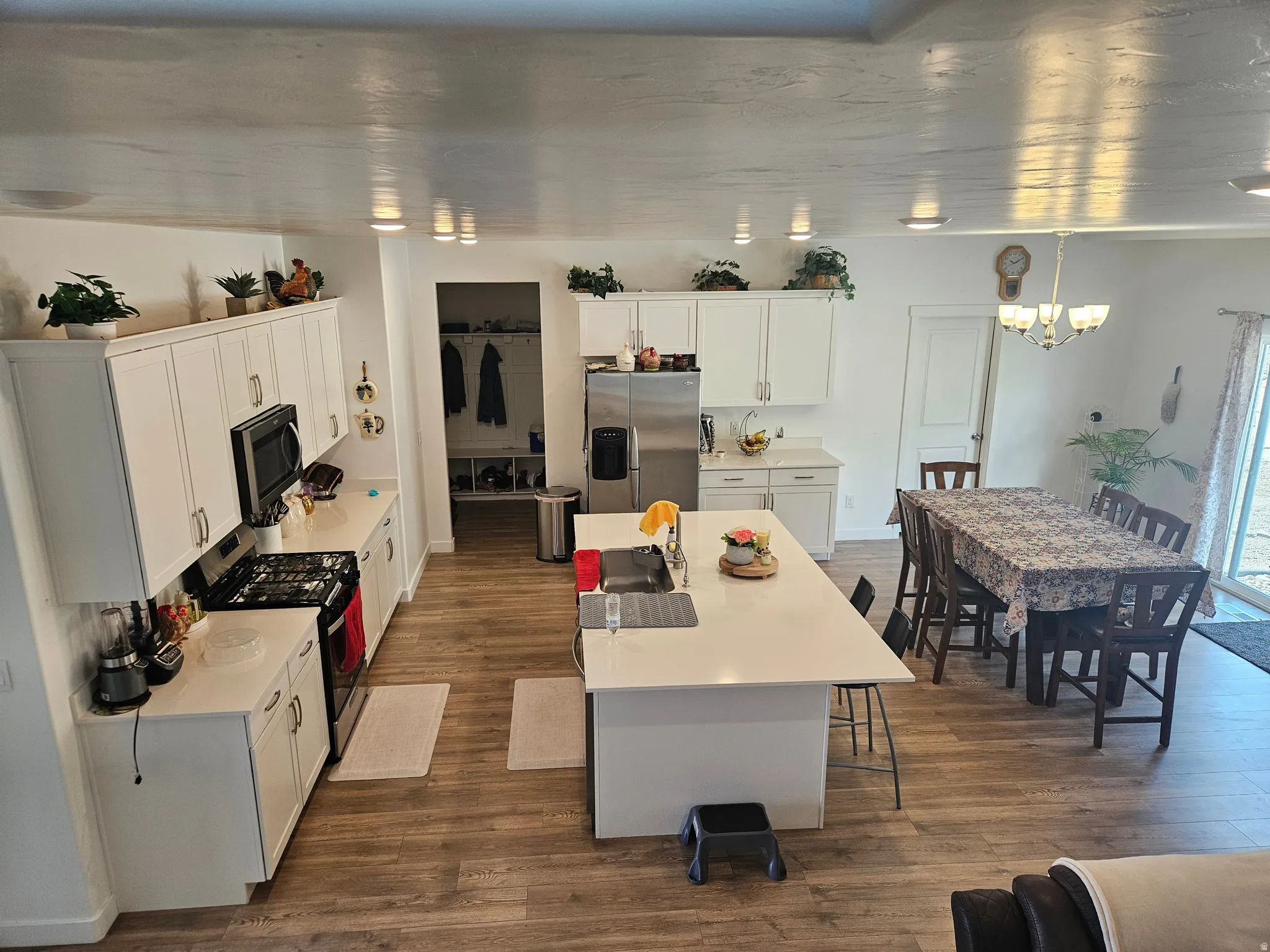 Contemporary kitchen with white cabinetry, stainless steel appliances, wood-finish flooring, recessed lighting, and an island with bar seating