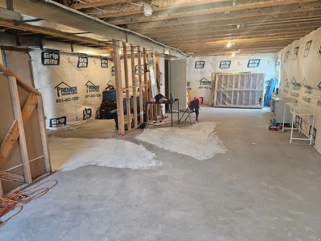 Unfinished basement space featuring exposed ceiling joists, concrete flooring, and partial wall framing